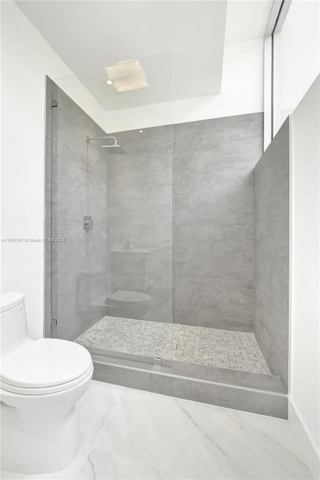 bathroom with a tile shower and toilet