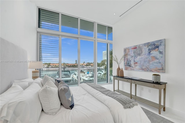 bedroom with a towering ceiling, a wall of windows, and multiple windows