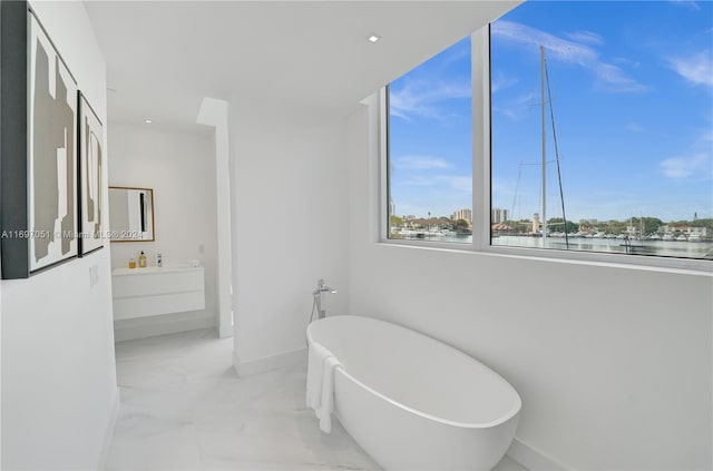 bathroom with vanity, a bathtub, and a water view