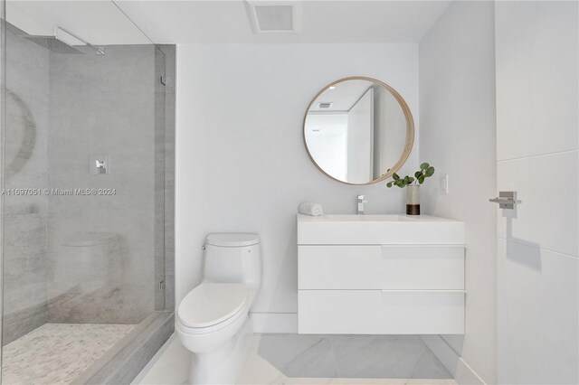 bathroom featuring vanity, toilet, and a tile shower