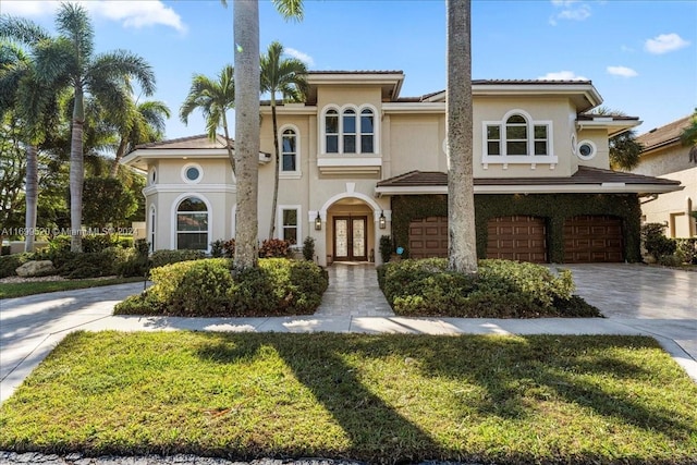 mediterranean / spanish-style home featuring french doors, a front yard, and a garage