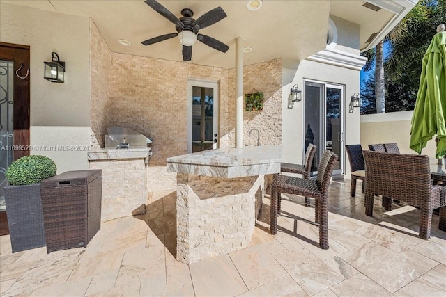 view of patio with grilling area, ceiling fan, an outdoor bar, and an outdoor kitchen