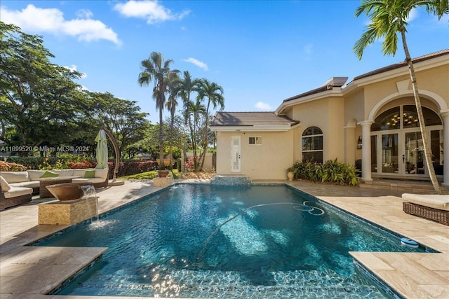 view of pool with french doors, pool water feature, and a patio area