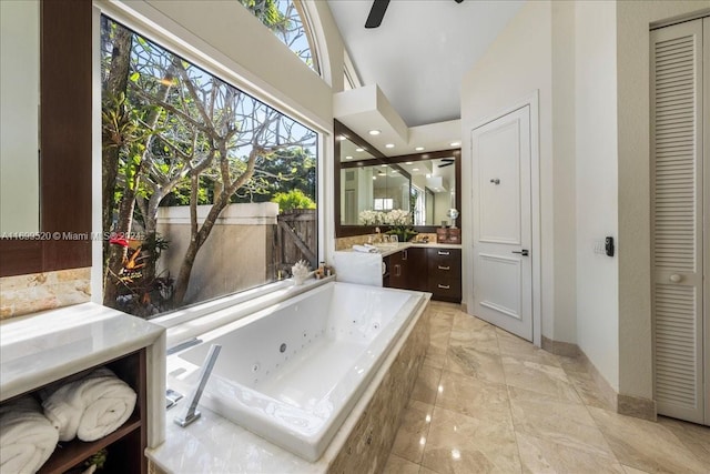 bathroom featuring vanity, vaulted ceiling, ceiling fan, and tiled tub