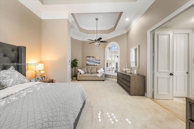 bedroom featuring ceiling fan, ornamental molding, light carpet, and a tray ceiling