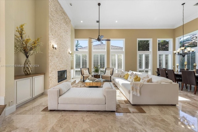 living room featuring a high end fireplace, ceiling fan with notable chandelier, and crown molding