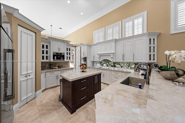 kitchen featuring light stone countertops, sink, pendant lighting, white cabinets, and ornamental molding