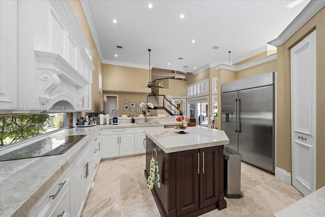 kitchen with white cabinetry, ceiling fan, stainless steel built in refrigerator, black electric cooktop, and ornamental molding