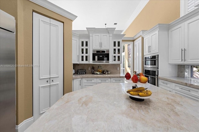 kitchen with backsplash, light stone counters, ornamental molding, stainless steel appliances, and white cabinets