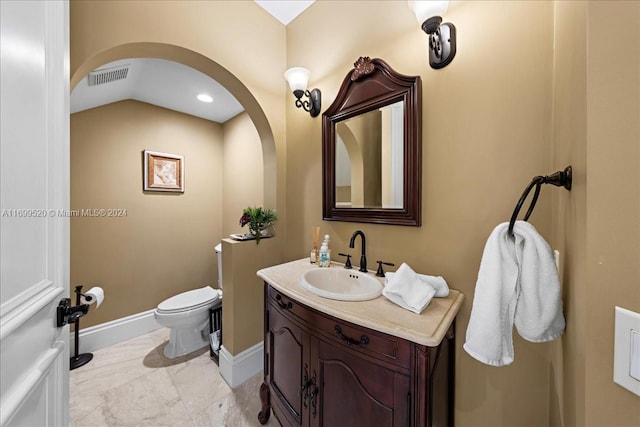 bathroom with vanity, toilet, and lofted ceiling