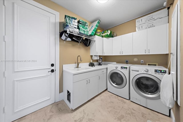 washroom featuring cabinets, a textured ceiling, washer and clothes dryer, and sink