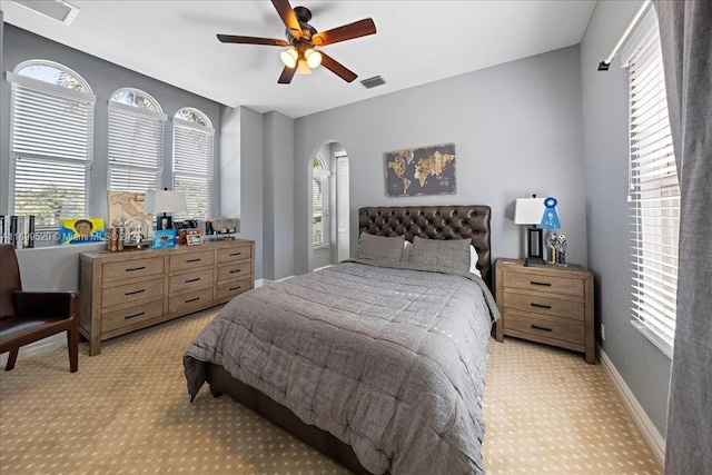 bedroom featuring ceiling fan, light carpet, and multiple windows