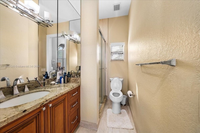 bathroom with tile patterned flooring, vanity, toilet, and a shower with door