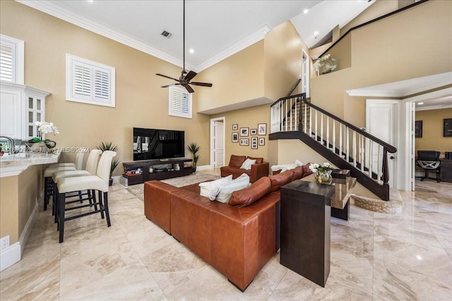 living room with ceiling fan, a towering ceiling, and ornamental molding