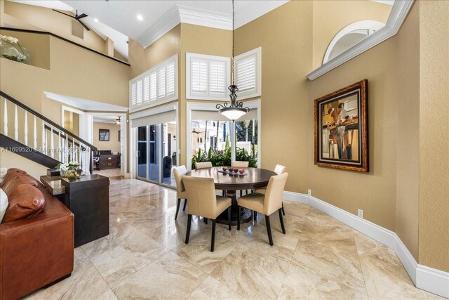 dining area featuring ceiling fan, crown molding, and a high ceiling