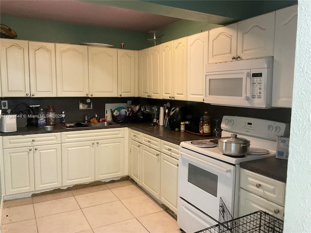 kitchen featuring white cabinets, light tile patterned flooring, white appliances, and sink