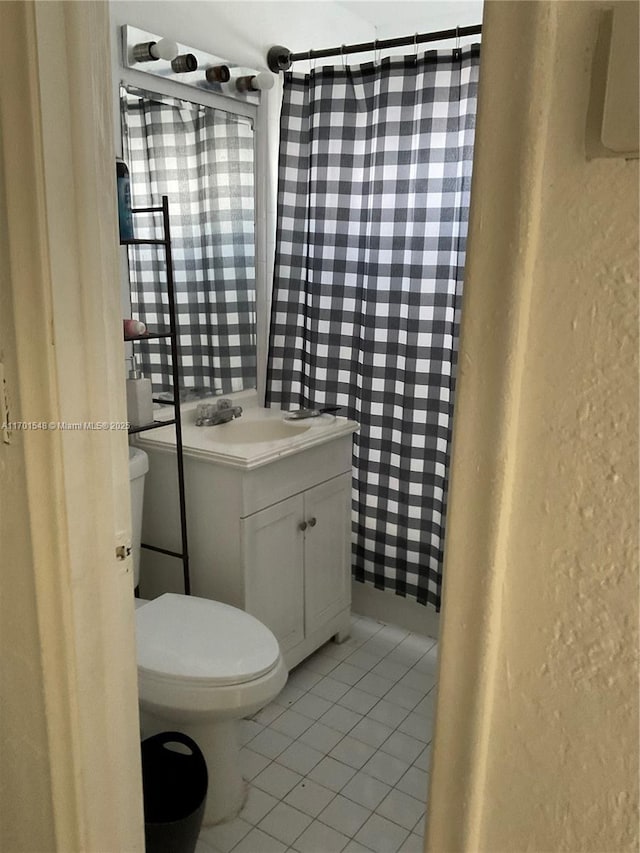 bathroom featuring tile patterned flooring, vanity, toilet, and walk in shower