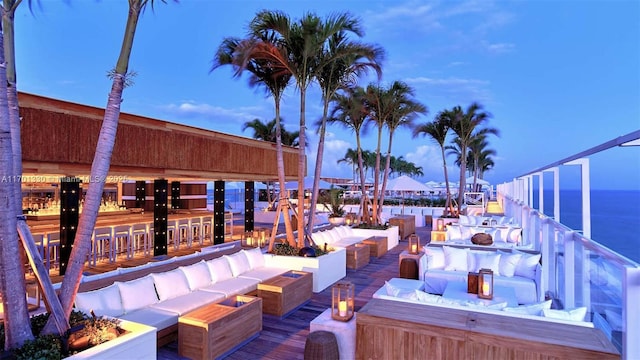 patio terrace at dusk featuring an outdoor living space with a fire pit and a water view