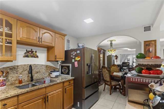 kitchen featuring stainless steel fridge, sink, light tile patterned flooring, and light stone counters