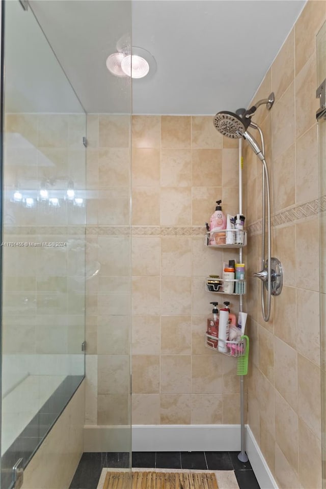 bathroom featuring tiled shower and tile patterned flooring