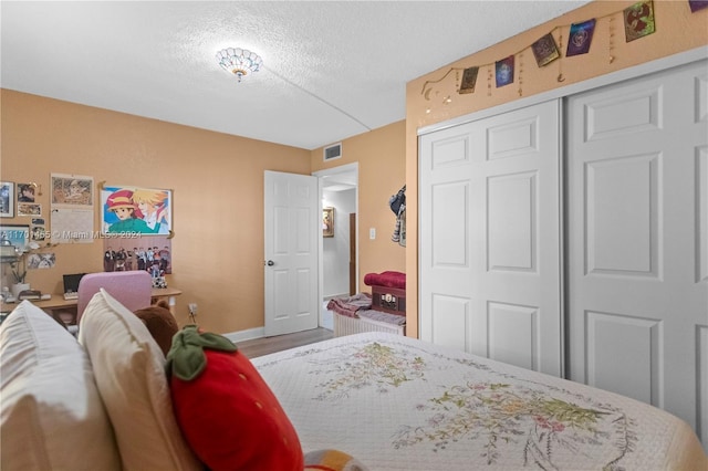 bedroom with a textured ceiling, hardwood / wood-style flooring, and a closet