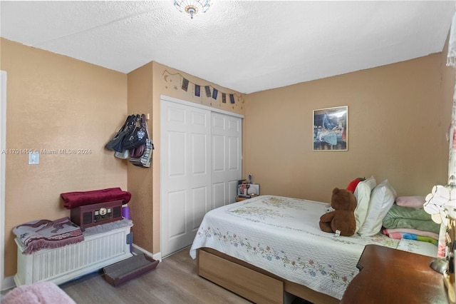 bedroom featuring wood-type flooring, a textured ceiling, and a closet