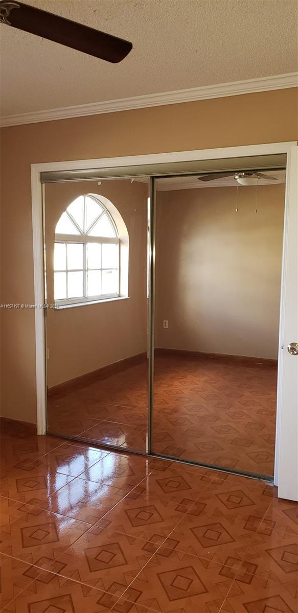 unfurnished bedroom featuring a textured ceiling, a closet, and crown molding