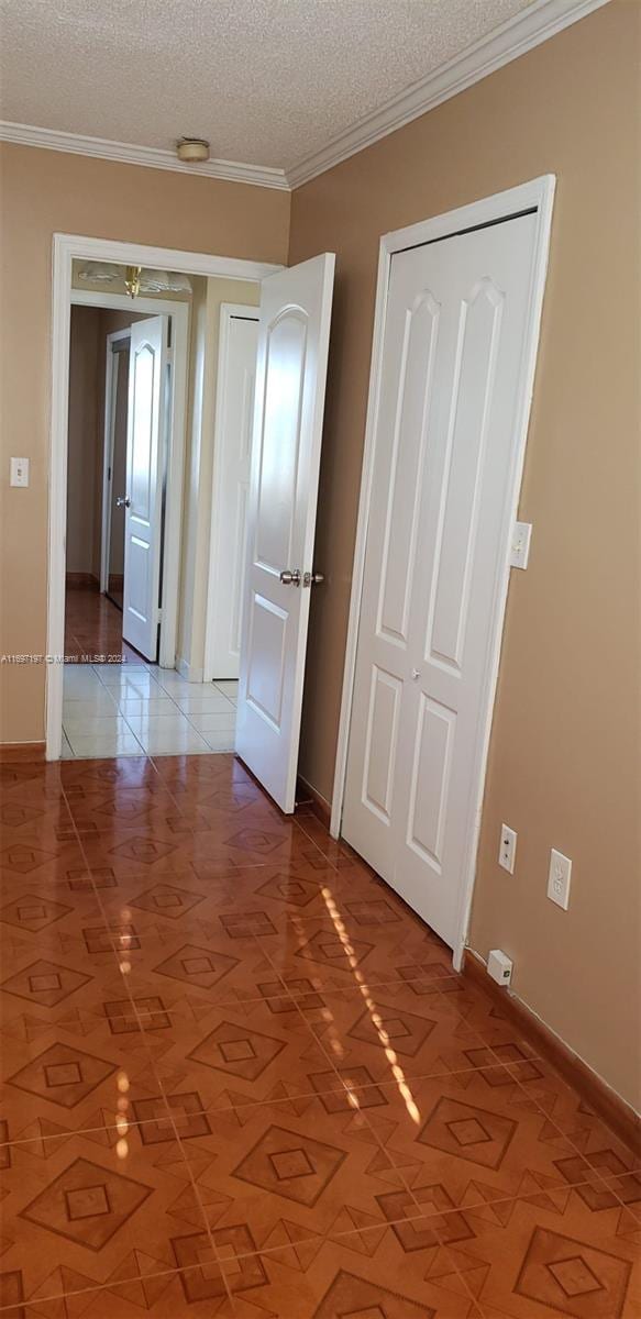 spare room featuring a textured ceiling, light tile patterned floors, and ornamental molding