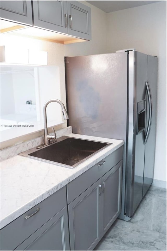 kitchen with gray cabinets, light stone counters, and sink