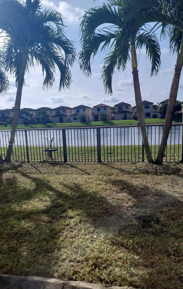 view of yard featuring a water view, fence, and a residential view