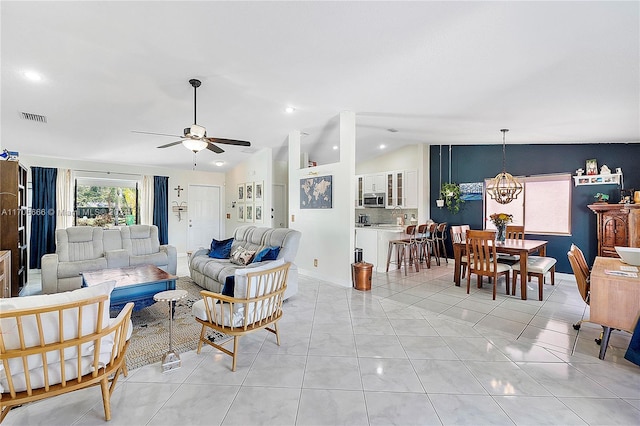 living room featuring ceiling fan with notable chandelier, light tile patterned flooring, and vaulted ceiling