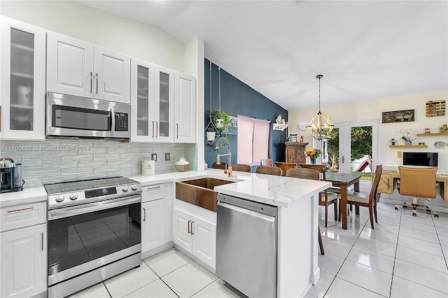 kitchen featuring white cabinets, pendant lighting, lofted ceiling, and appliances with stainless steel finishes