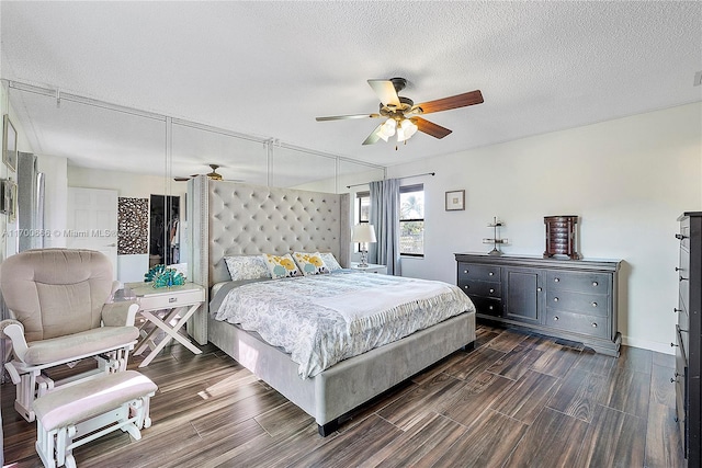 bedroom with a textured ceiling, ceiling fan, and dark wood-type flooring