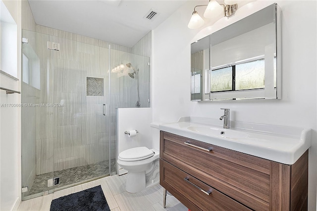 bathroom featuring a shower with door, vanity, and toilet