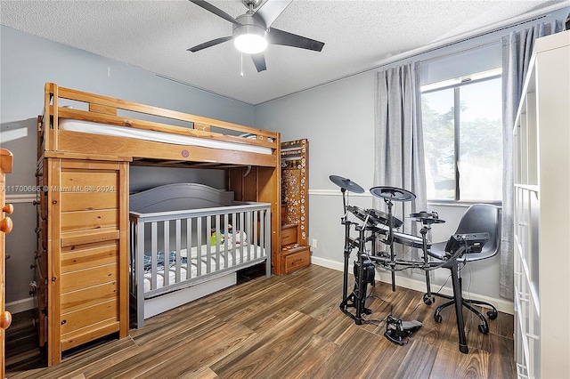 bedroom with dark hardwood / wood-style floors, a textured ceiling, and a nursery area