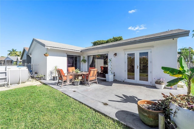 rear view of property featuring french doors, a patio area, and a lawn