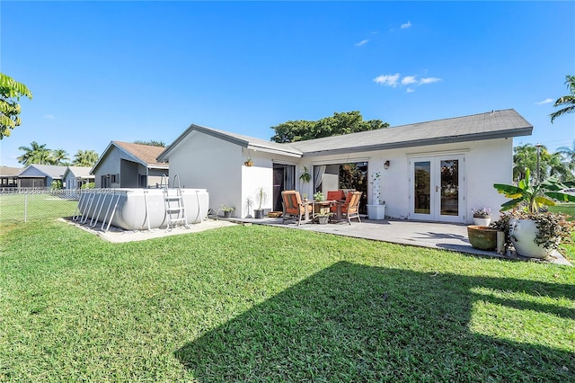 rear view of house featuring french doors, a patio, and a lawn