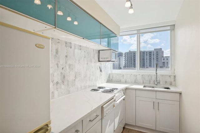 kitchen with tasteful backsplash, sink, hardwood / wood-style floors, and white appliances