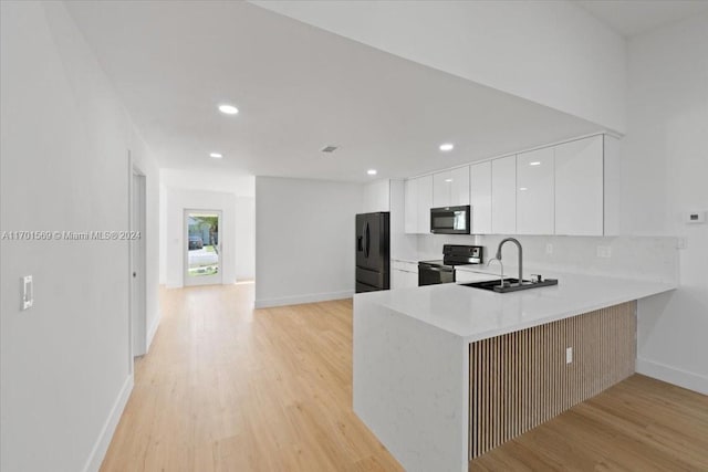 kitchen featuring black appliances, light hardwood / wood-style floors, white cabinets, and sink