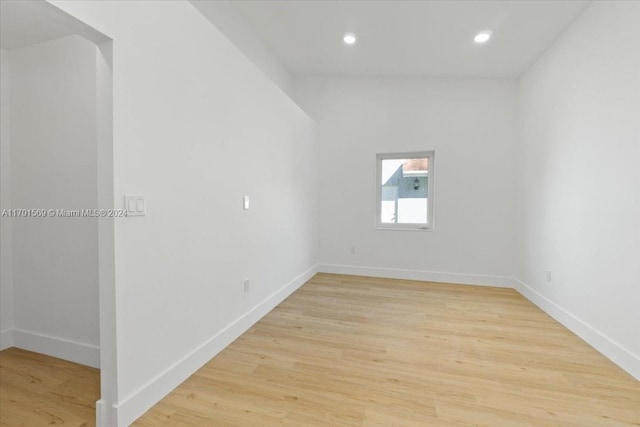 spare room with lofted ceiling and light hardwood / wood-style flooring