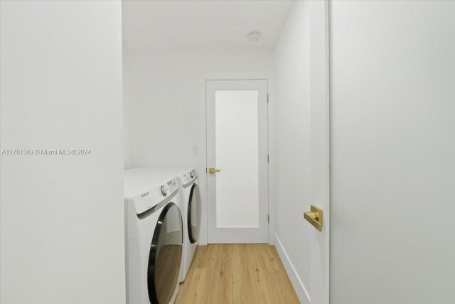 washroom featuring washing machine and dryer and light hardwood / wood-style floors