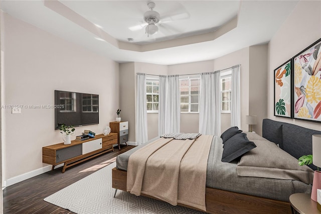 bedroom featuring ceiling fan, a raised ceiling, and dark hardwood / wood-style flooring