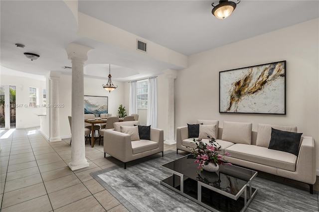 living room featuring decorative columns and light tile patterned flooring