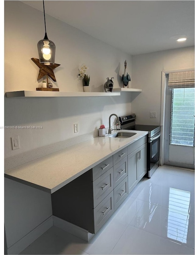 kitchen with pendant lighting, stainless steel electric range oven, gray cabinetry, and sink