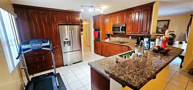 kitchen with kitchen peninsula, sink, light tile patterned floors, and appliances with stainless steel finishes