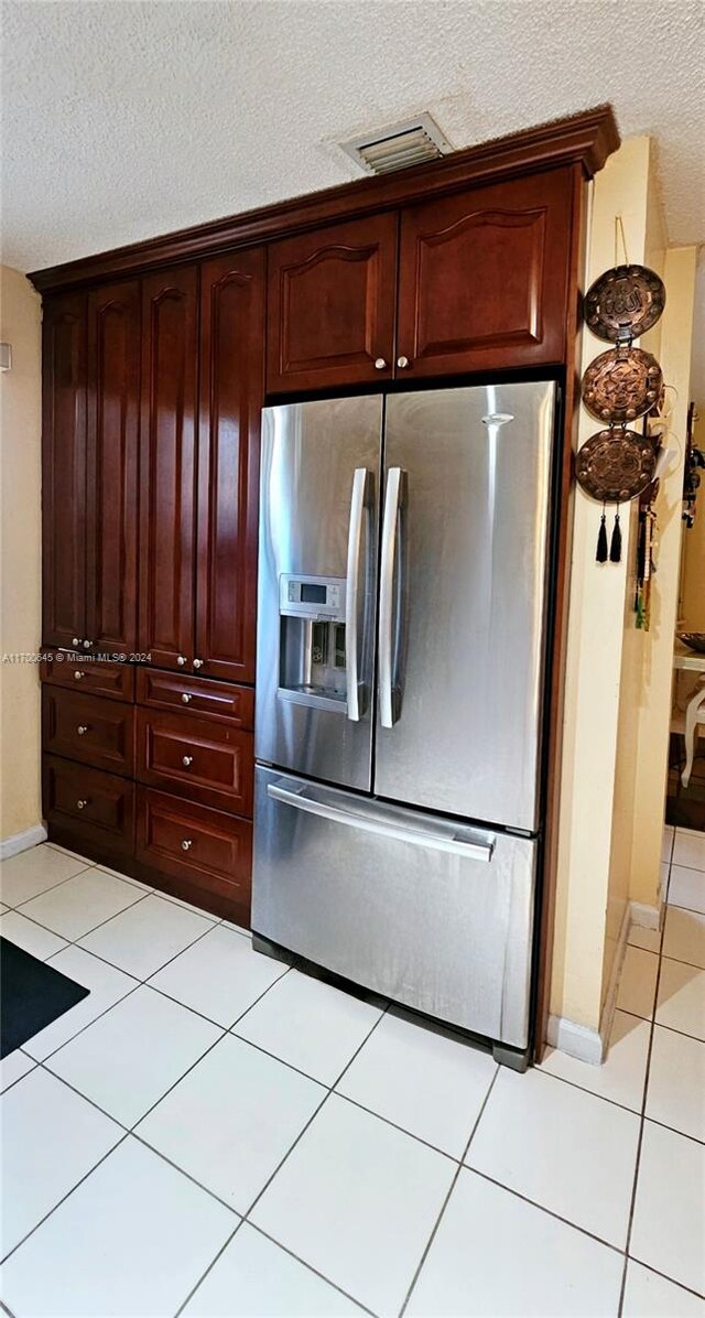 kitchen featuring stainless steel fridge, light tile patterned floors, and a textured ceiling