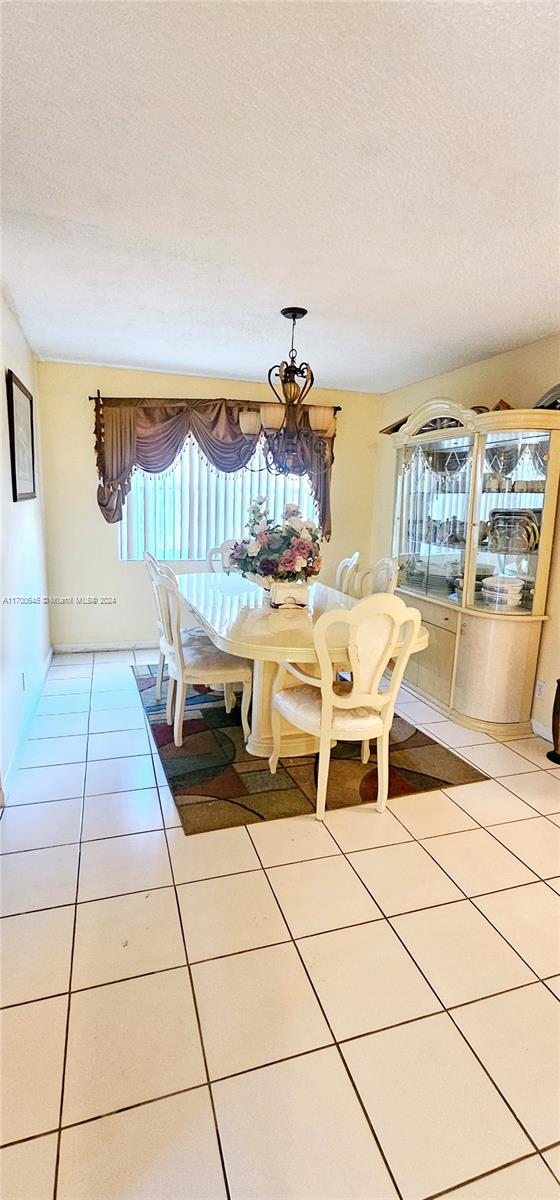 dining area with tile patterned flooring, a notable chandelier, and a textured ceiling