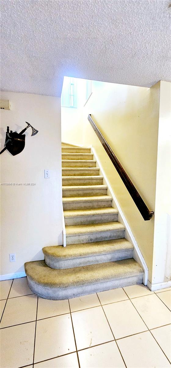 stairs with tile patterned flooring and a textured ceiling