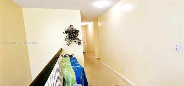 hallway with a textured ceiling and light carpet