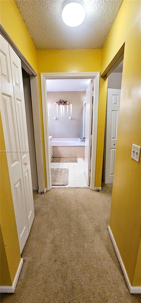 17352 SW 18th St, Miramar, FL 33029 - hallway featuring a textured ceiling and carpet flooring